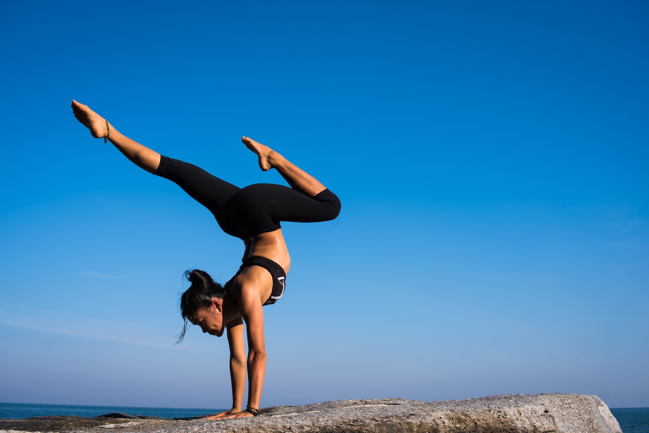 woman doing a hand stand yoga pose on a rock
