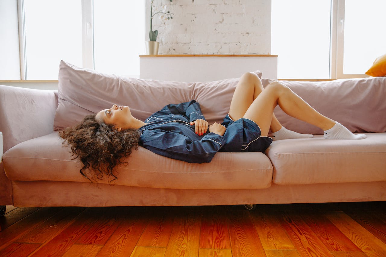 woman lying on couch bloated and holding stomach