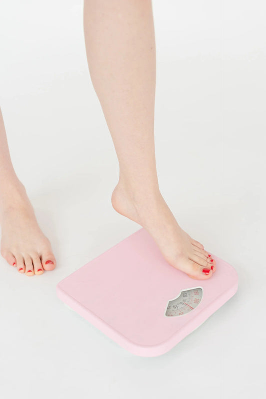 woman stepping on scale to see if drinking matcha for weight loss helped achieve results